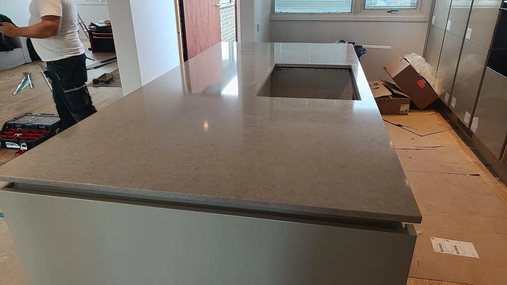 Poleret køkkenø i Silestone Royal Reef, gråbeige kvartskomposit, med stort rektangulärt udskæring i ett køkken i Limhamn.