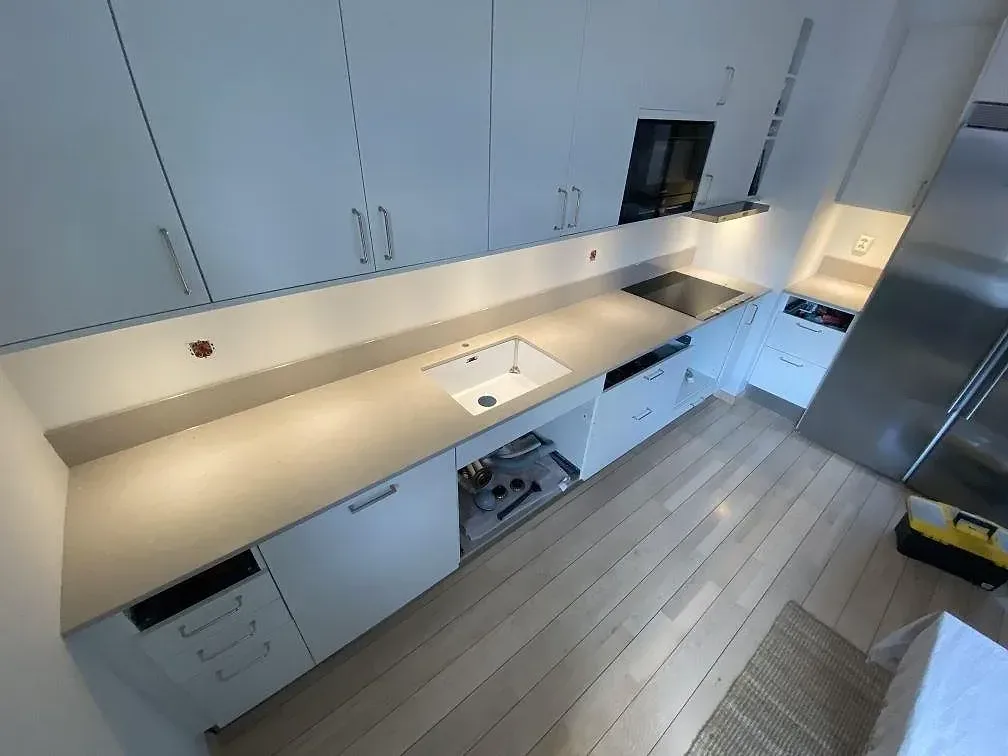 Køkkenbordplade i beige Silestone Royal Reef, poleret, längs en sammanhängande bänkrad med hvid underlimmad vask og infälld induktionshäll i ett køkken i Lund.