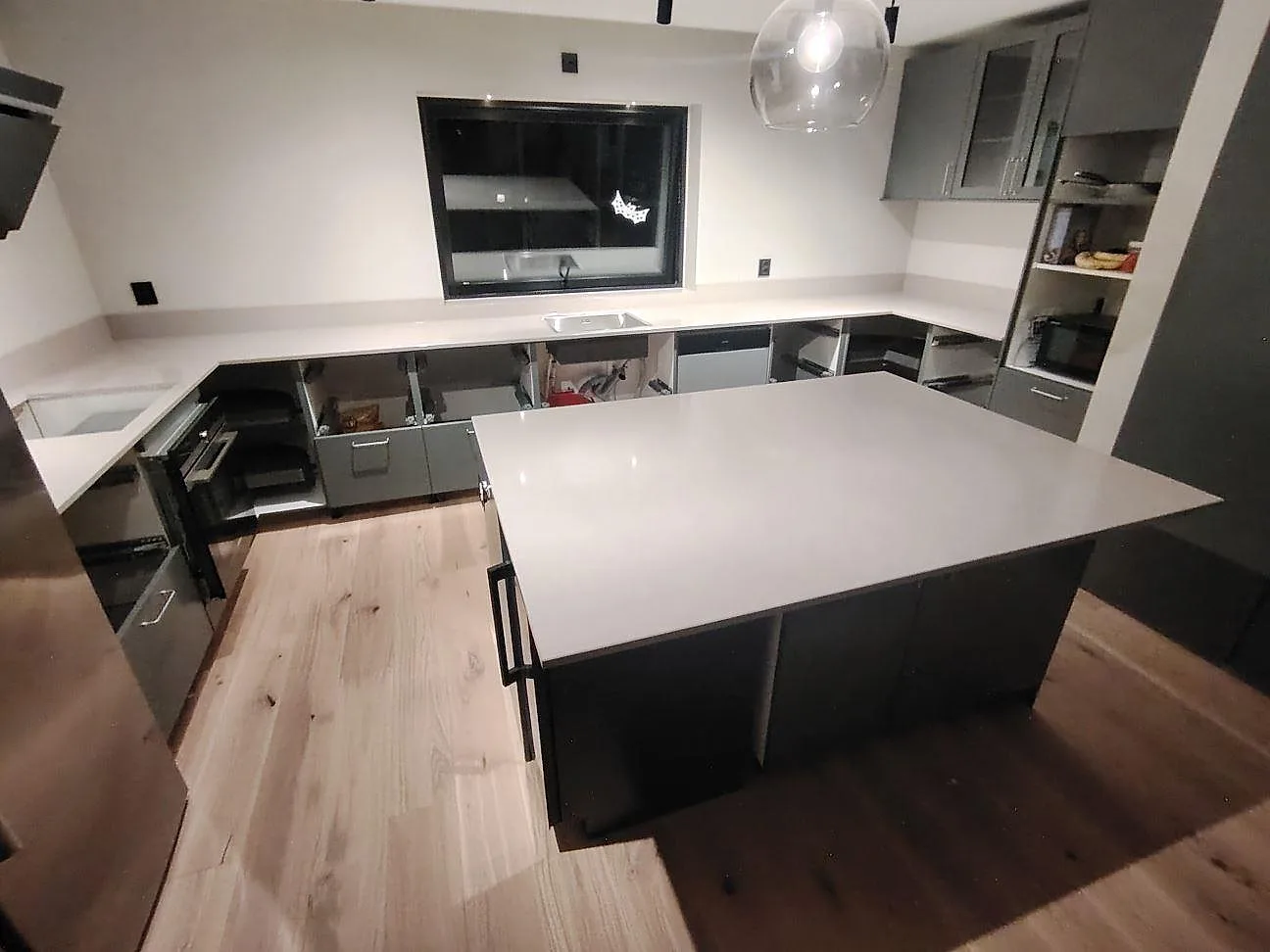Køkkenbordplader og køkkenø i lys Silestone Royal Reef, poleret kvartskomposit, i ett køkken under montering i Västerås.