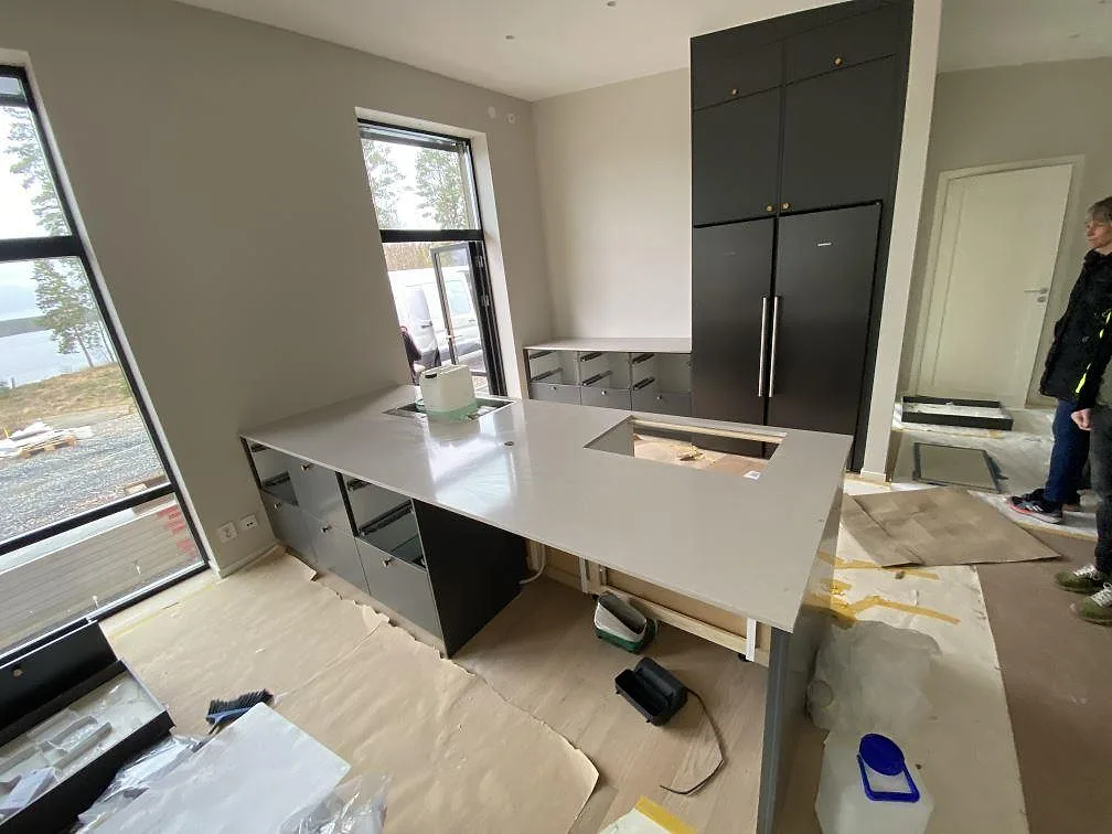 Køkkenø i lys Silestone Royal Reef, poleret, nymonterad i ett køkken med mörkgrå fronter og sjöutsikt i Vaggeryd.
