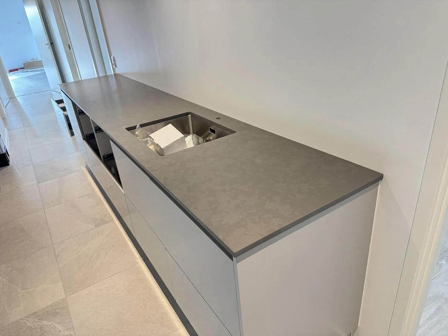 Køkkenbordplade i grå Silestone Seaport komposit, mat Mocka-overflade, med rostfri vask i ett køkken under montering i Kolind.