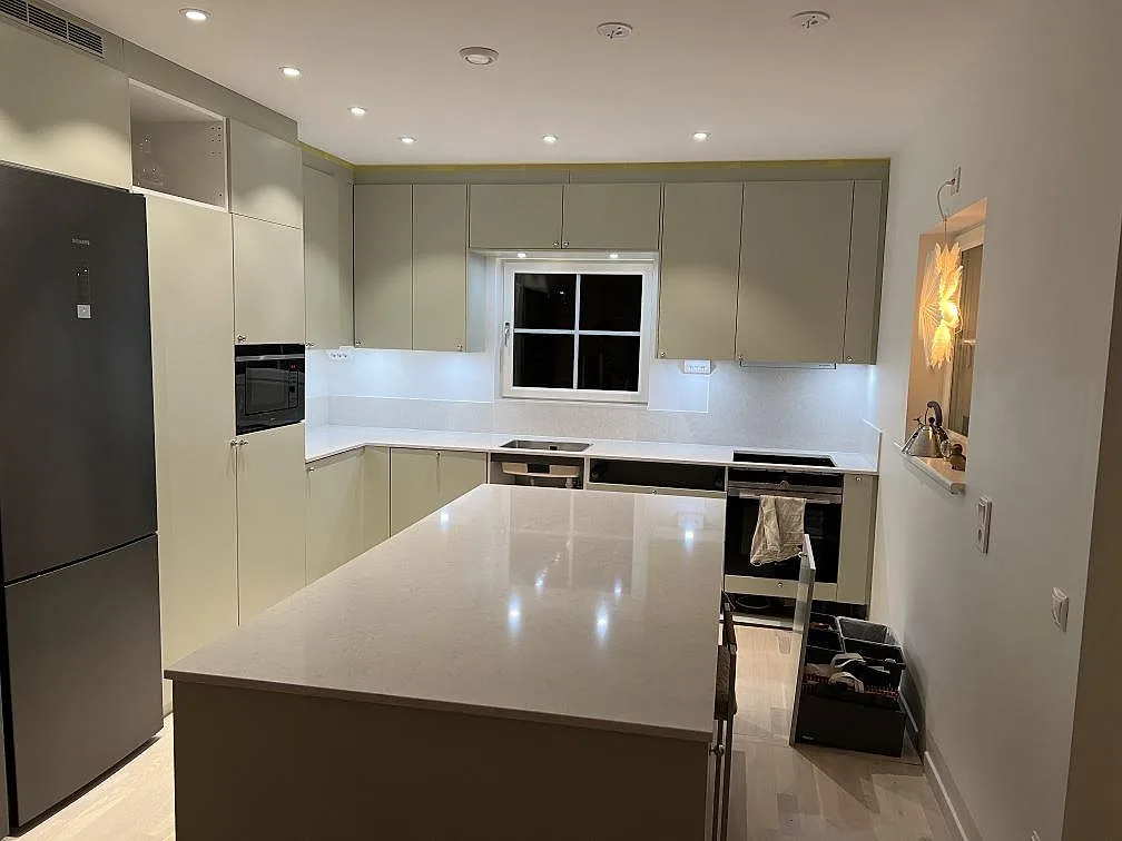 Køkkenbordplade og køkkenø i poleret Silestone Snowy Ibiza, lys kvartskomposit med lavt stænkplade i ett køkken i Åkersberga.