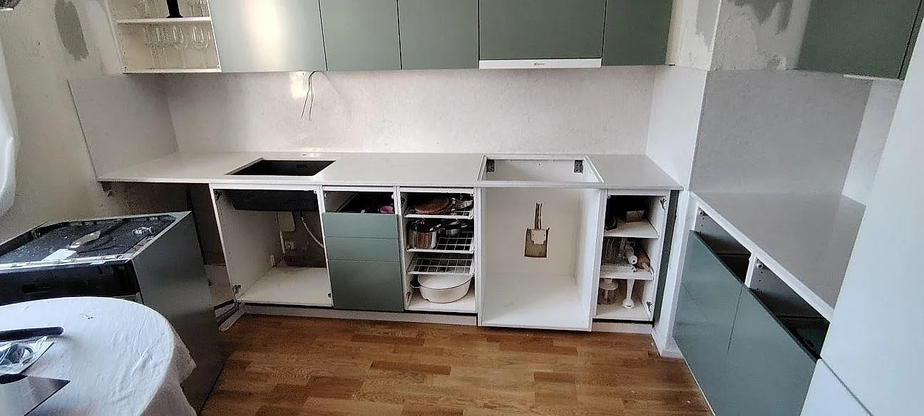 Køkkenbordplade i hvid Silestone Snowy Ibiza, poleret kvartskomposit, längs en grøn köksinredning under montering i Årsta.