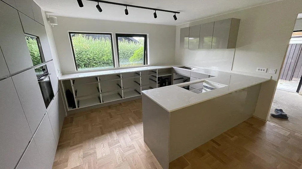 Poleret køkkenbordplade i Silestone Snowy Ibiza, hvid kvartskomposit med 12 mm stænkplade i ett køkken under montering i Bjärred.