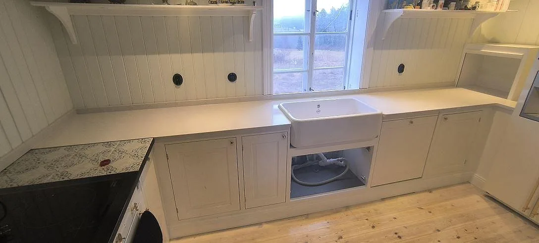 Køkkenbordplade i hvid poleret Silestone Snowy Ibiza längs en væg med vindue i ett køkken i Björnlunda.