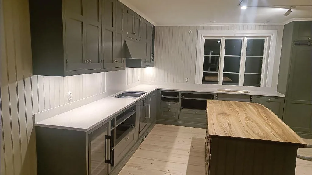 Køkkenbordplade i poleret Silestone Snowy Ibiza, hvid komposit, monteret i ett L-format køkken med uppvikt stänkkant i Braås.