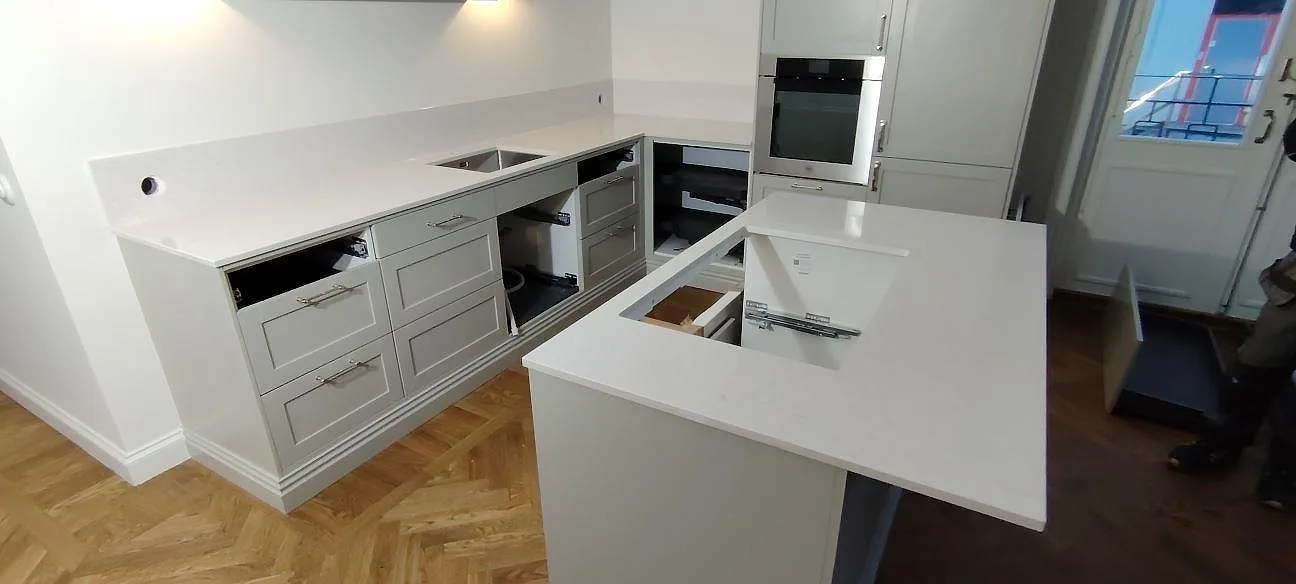 Poleret køkkenbordplade i Silestone Snowy Ibiza med køkkenø, väggbänk og uppvikt stänkkant i ett køkken i Bromma.