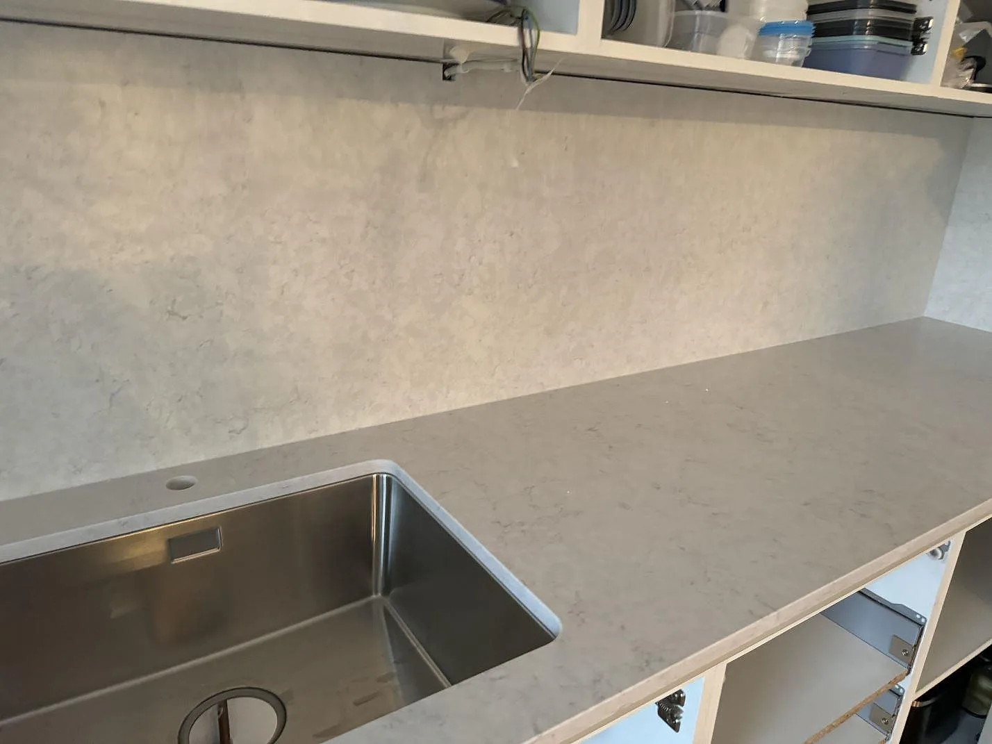 Køkkenbordplade i poleret Silestone Snowy Ibiza komposit med rostfri vask og vægbeklædning i ett køkken i Helsingborg.