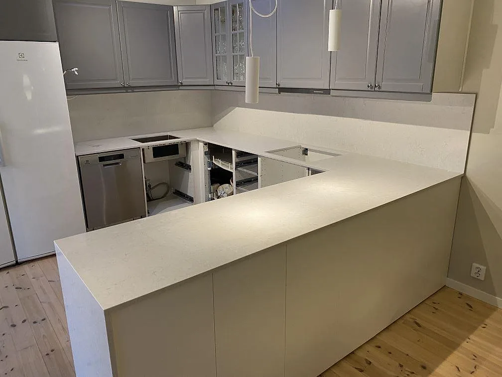 Køkkenbordplade i poleret Silestone Snowy Ibiza, hvid kvartskomposit, monteret i ett U-format køkken med låg stänkkant i Kungsbacka.