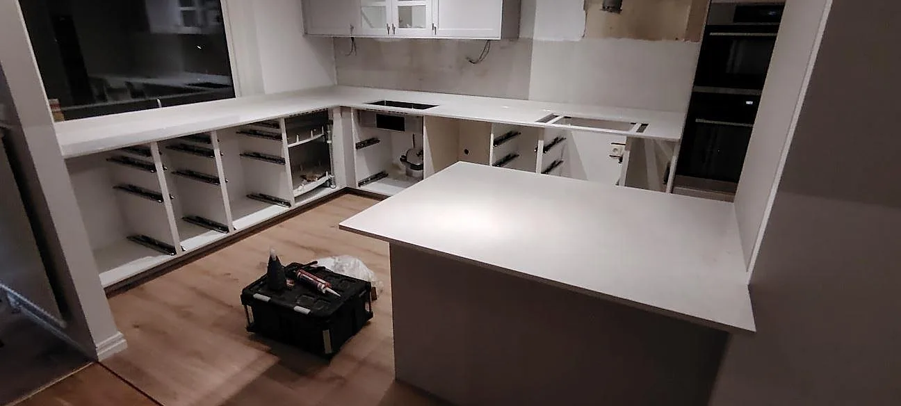 Poleret køkkenbordplade og køkkenø i Silestone Snowy Ibiza, kvartskomposit, under montering i ett køkken i Linköping.