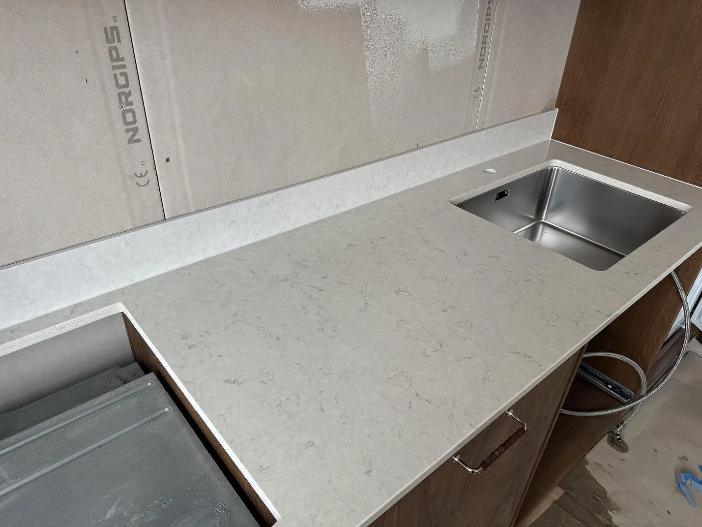 Køkkenbordplade i poleret Silestone Snowy Ibiza komposit med hällurtag, rostfri vask og låg stänkkant i Lund.