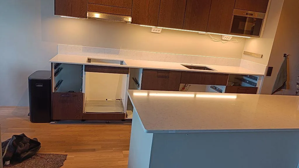 Køkkenbordplade i poleret Silestone Snowy Ibiza, hvid kvartskomposit, med låg stänkkant og öppen köksinredning under montering i Malmö.