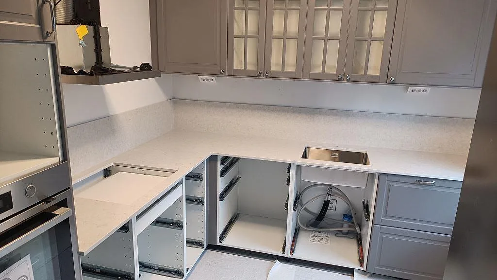 L-format køkken i Malmö med poleret Silestone Snowy Ibiza som køkkenbordplade, matchande stænkplade, rostfri vask og hällurtag.