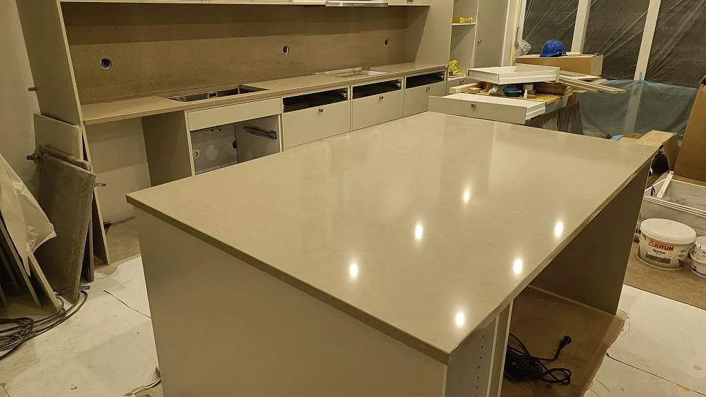 Køkkenbordplade i lys Silestone Snowy Ibiza, poleret, med stor arbetsö og vægbeklædning i Silestone Coral Clay i Malmö.
