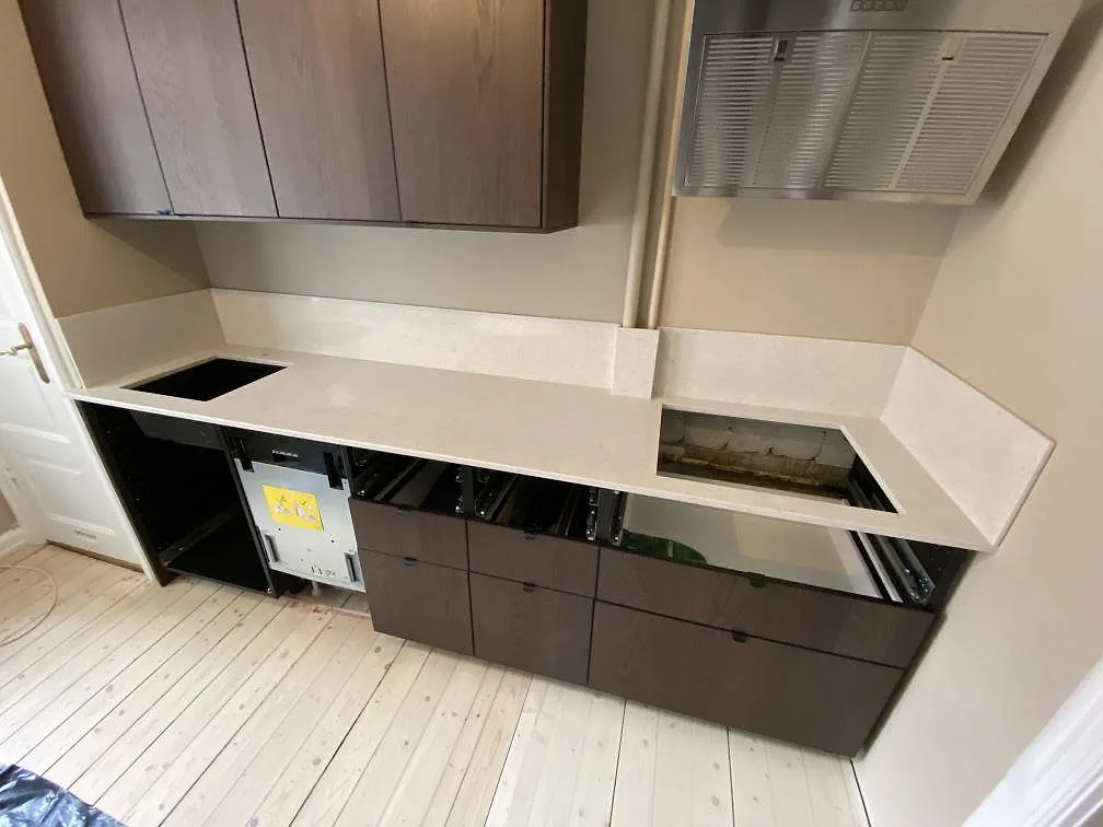 Køkkenbordplade i poleret Silestone Snowy Ibiza-kvartskomposit med stænkplade, mørk vask og hällöppning i ett køkken under montering i Malmö.