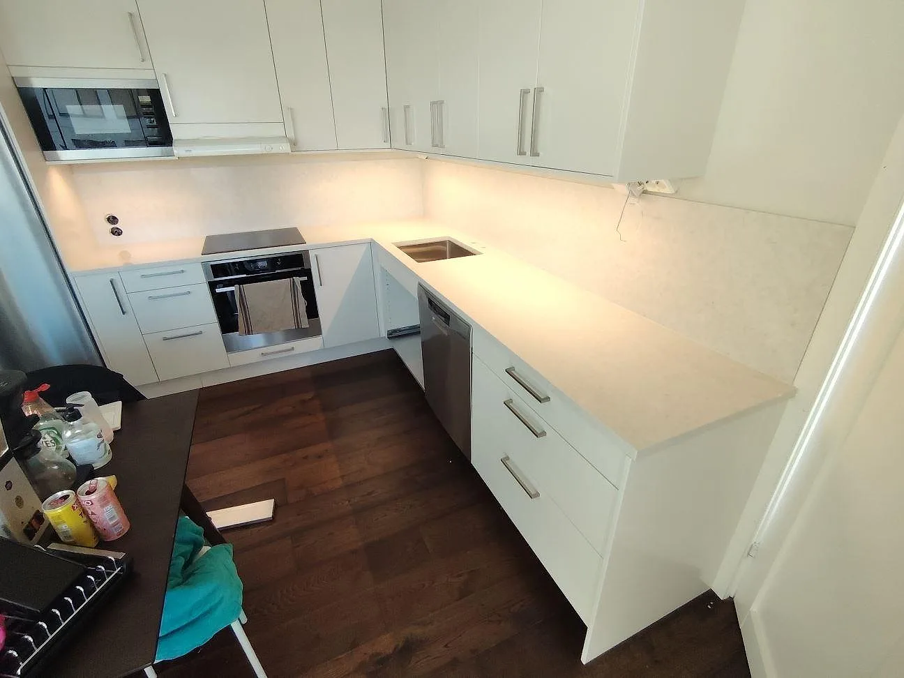 Poleret køkkenbordplade i komposit, Silestone Snowy Ibiza, med matchande vægbeklædning i ett vitt køkken i Solna.