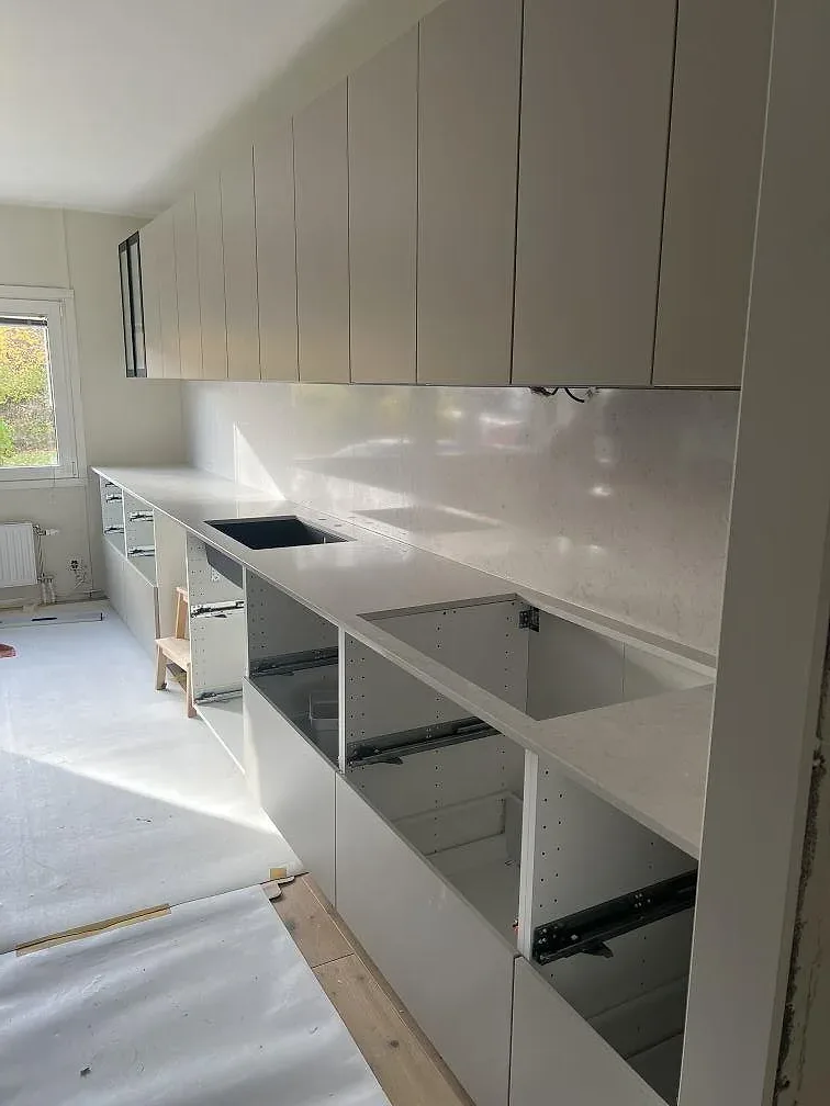Køkkenbordplade i hvid Silestone Snowy Ibiza komposit, poleret, med matchande stænkplade og öppna köksstommar i Stockholm.