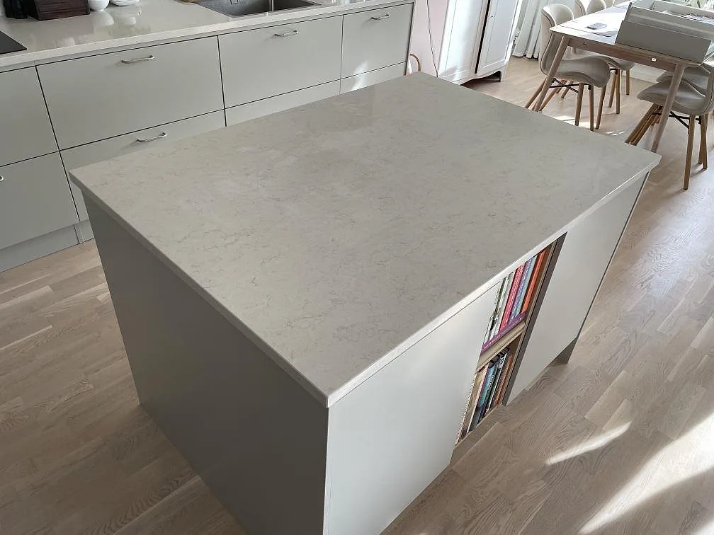 Køkkenbordplade i poleret Silestone Snowy Ibiza, 30 mm kvartskomposit, med stor køkkenø og bänkrad i ett køkken i Stockholm.