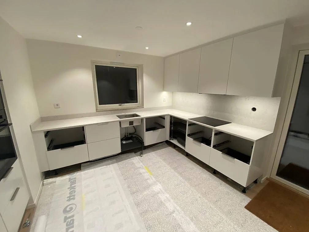 U-format køkken i Strandbaden med køkkenbordplade i Silestone Snowy Ibiza, poleret lys kvartskomposit, stænkplade i samme sten, rostfri vask og sort kogeplade.