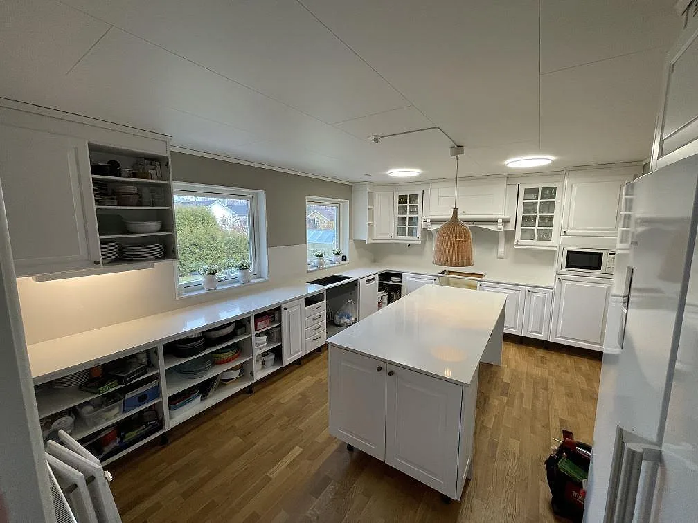 Køkkenbordplade og køkkenø i lys poleret Silestone Yukon komposit i ett vitt køkken i Eskilstuna.
