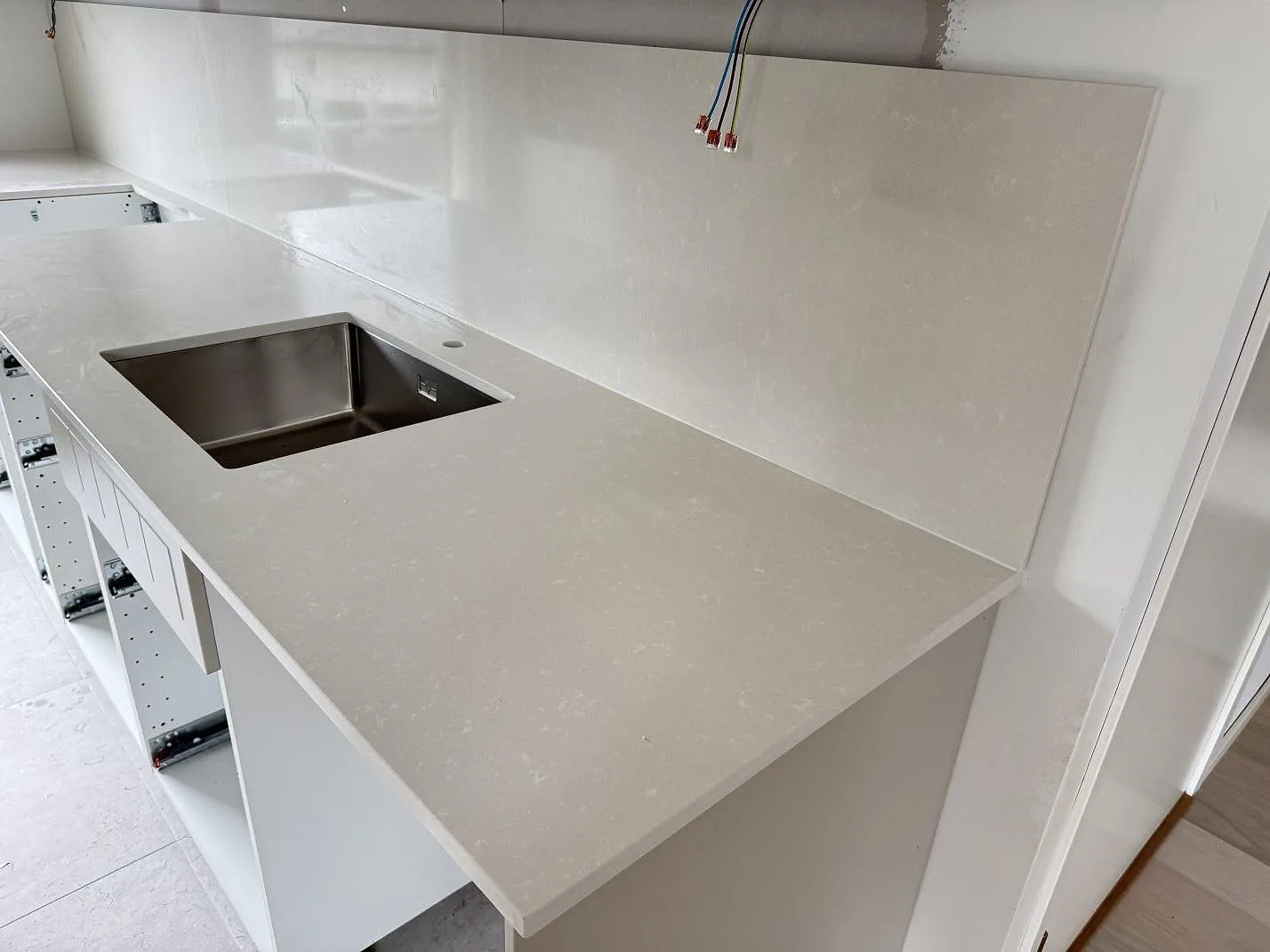 Køkkenbordplade i poleret Silestone Yukon komposit med rostfri vask og matchande vægbeklædning i ett køkken i Råå.