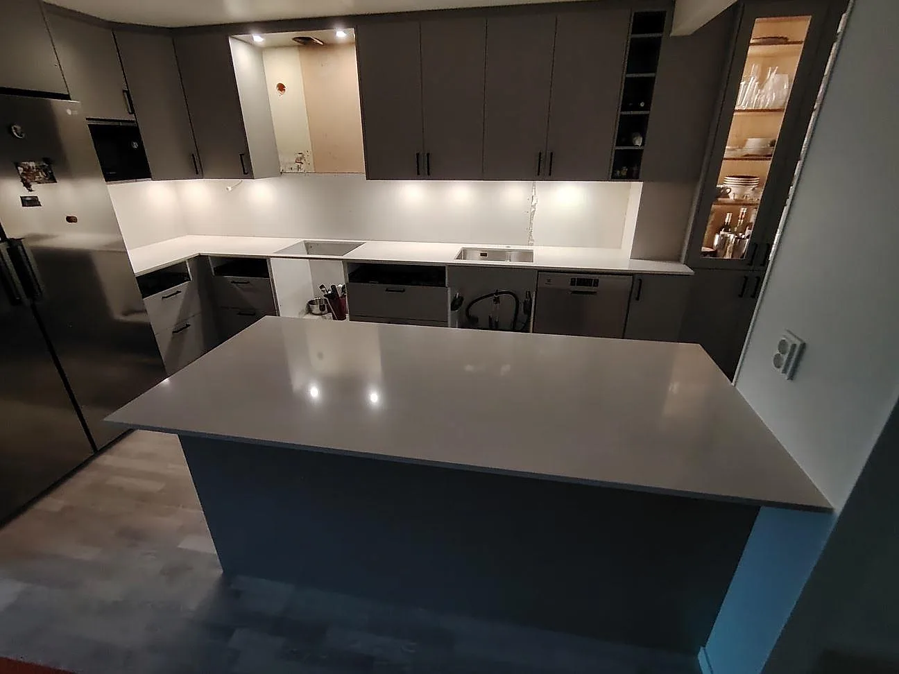Poleret køkkenbordplade i hvid Silestone Yukon, 20 mm kvartskomposit, med L-formad bänkrad og køkkenø i ett køkken i Västerås.