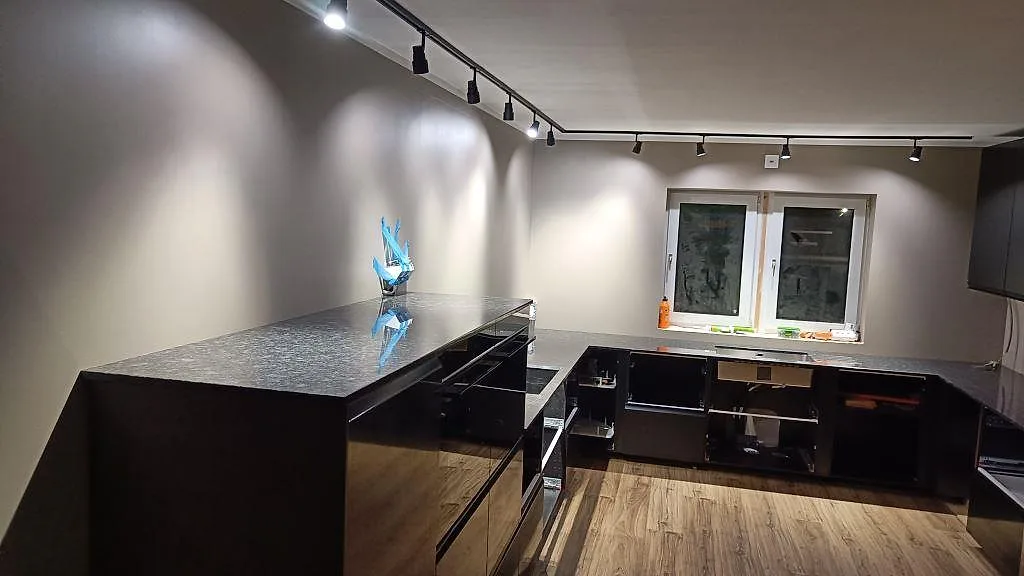 Køkkenbordplade i poleret Steel Grey granit, 20 mm, monteret på mørke köksstommar i ett køkken i Nybro.