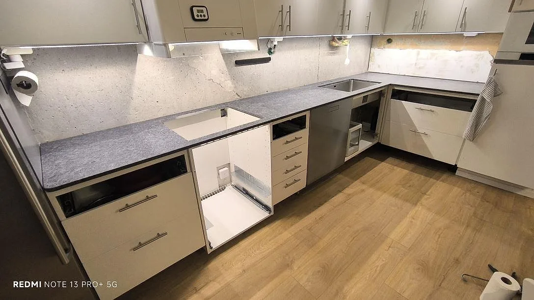 L-formad køkkenbordplade i mat Steel Grey granit med vask og hällurtag i ett køkken i Sollentuna.