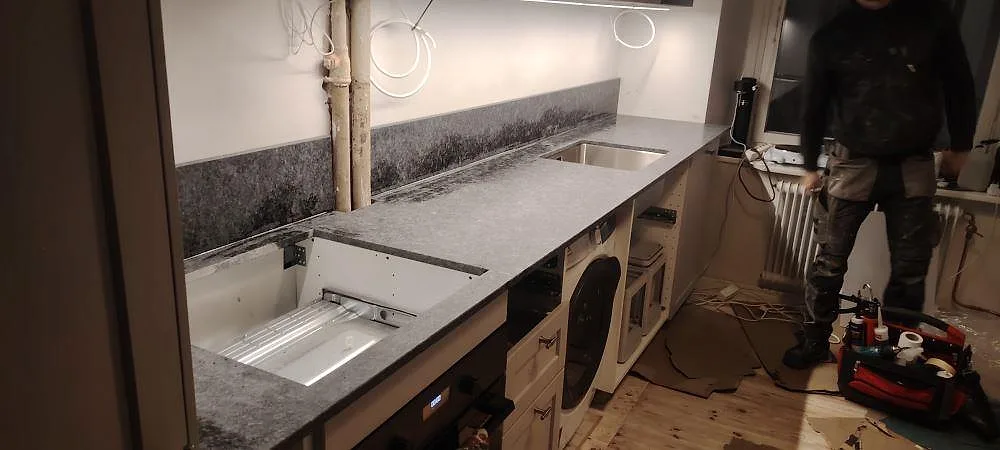 Køkkenbordplade i mat Steel Grey granit, 20 mm, med underlimmad vask og stänkkant under montering i Stockholm.