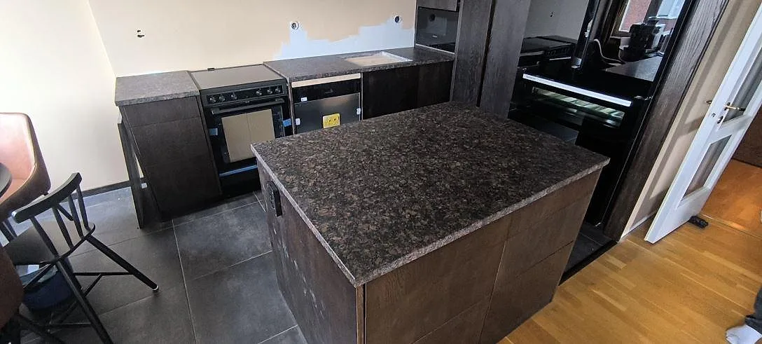 Køkkenø og Bordplader i mørk Tan Brown granit, mat overflade, under montering i ett køkken i Farsta.