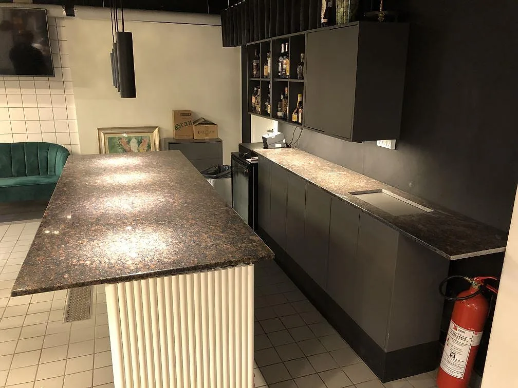 Køkkenbordplade i poleret Tan Brown granit med frihängande bardel på hvid sockel, mørke köksstommar og bruna, svarta og rödbruna toner i ett køkken i Hellerup.
