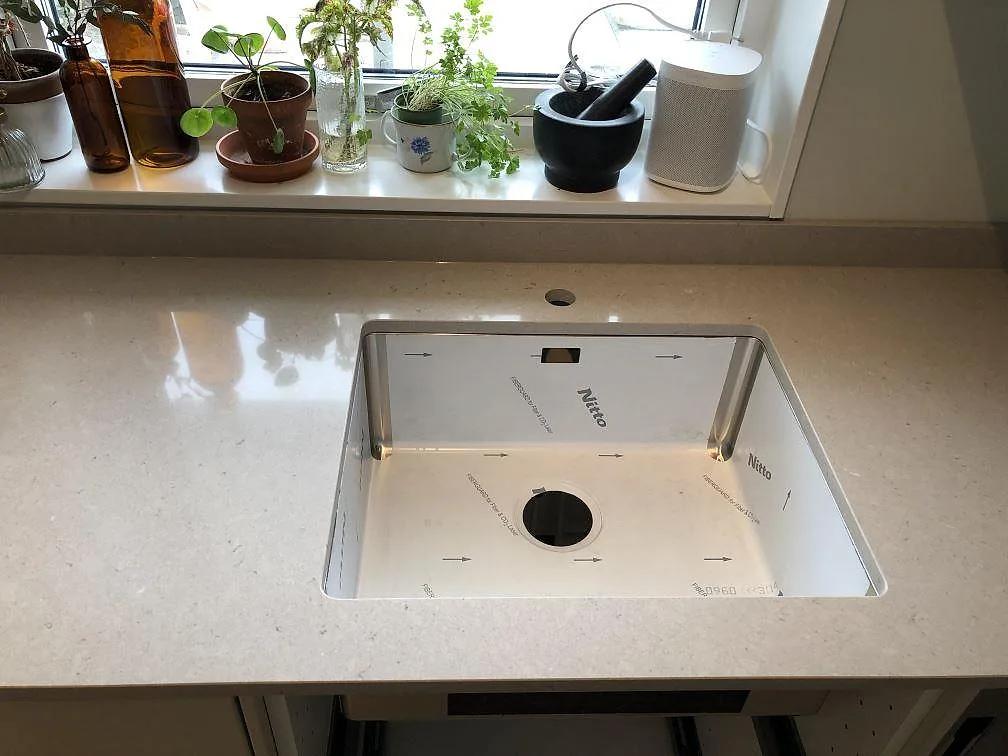 Poleret køkkenbordplade i Technistone Crystal Absolute White vid diskhoområdet under vindue i Skanör.