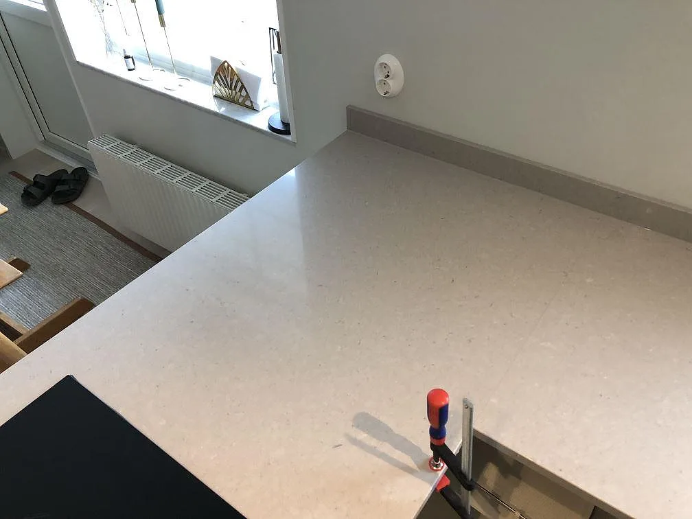 Lys poleret kompositskiva i Technistone Crystal Absolute White med låg stänkkant og hälldetalj i køkken i Skanör.