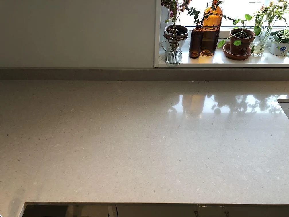 Närbild af blank Technistone Crystal Absolute White som køkkenbordplade under vindue med reflektioner i Skanör.