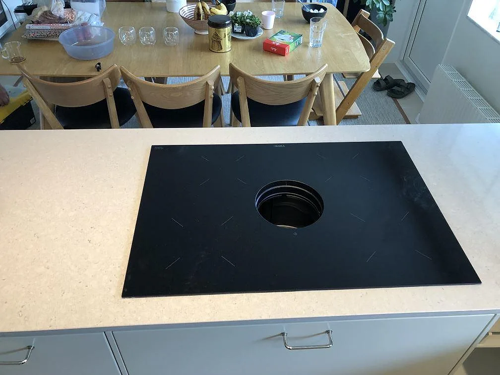 Detalj af poleret Technistone Crystal Absolute White som køkkenbordplade med sort kogeplade på kökshalvö i Skanör.