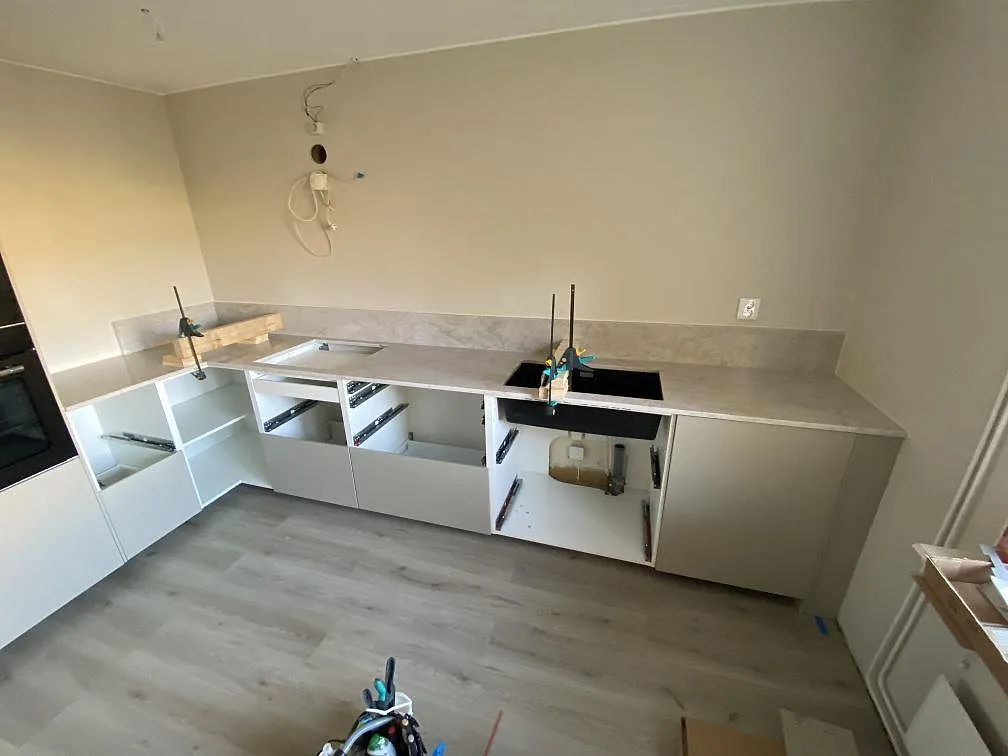 Køkkenbordplade i Technistone Glencoe komposit, 20 mm poleret, med stænkplade i ett køkken under montering i Malmö.