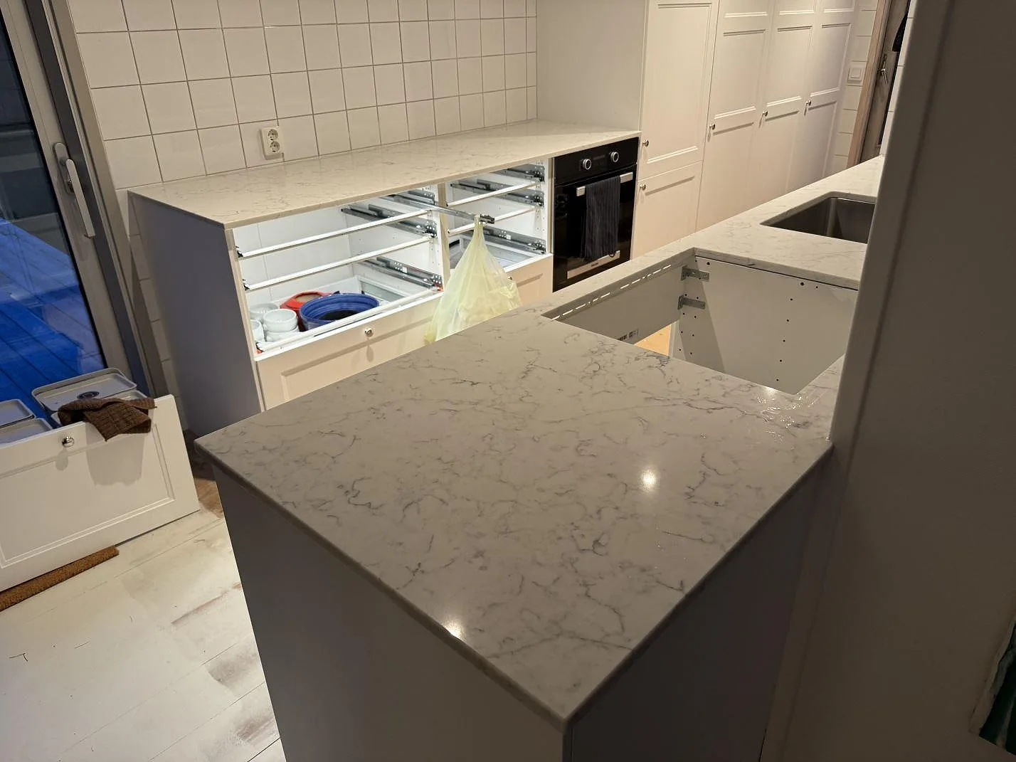 Køkkenbordplade i Technistone Mystery White komposit, poleret, med rostfri vask og hällöppning i ett køkken under montering i Nyehusen.