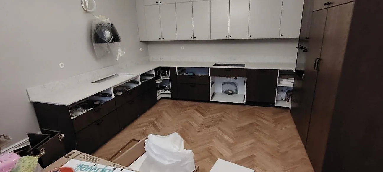 Køkkenbordplade i hvid Technistone Mystery White kvartskomposit, 20 mm poleret, med synlig kogeplade og mørke underskåp i ett køkken i Stockholm med fiskbensgolv.