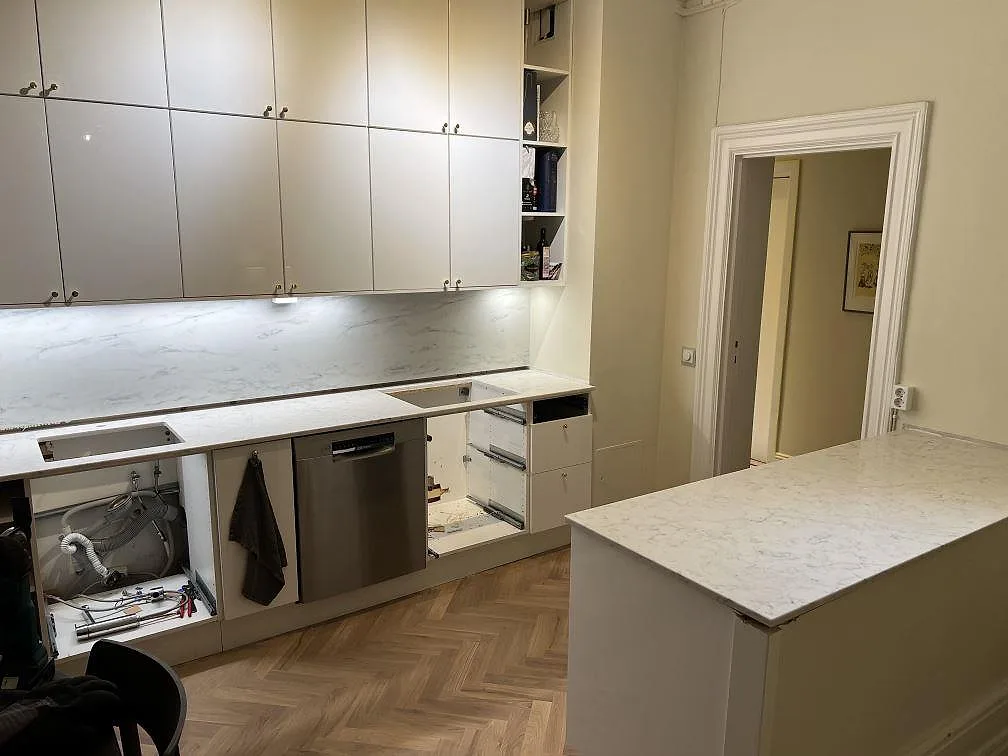 Køkkenbordplade i poleret Technistone Mystery White komposit med väggsida og køkkenø i ett køkken i Stockholm under montering.