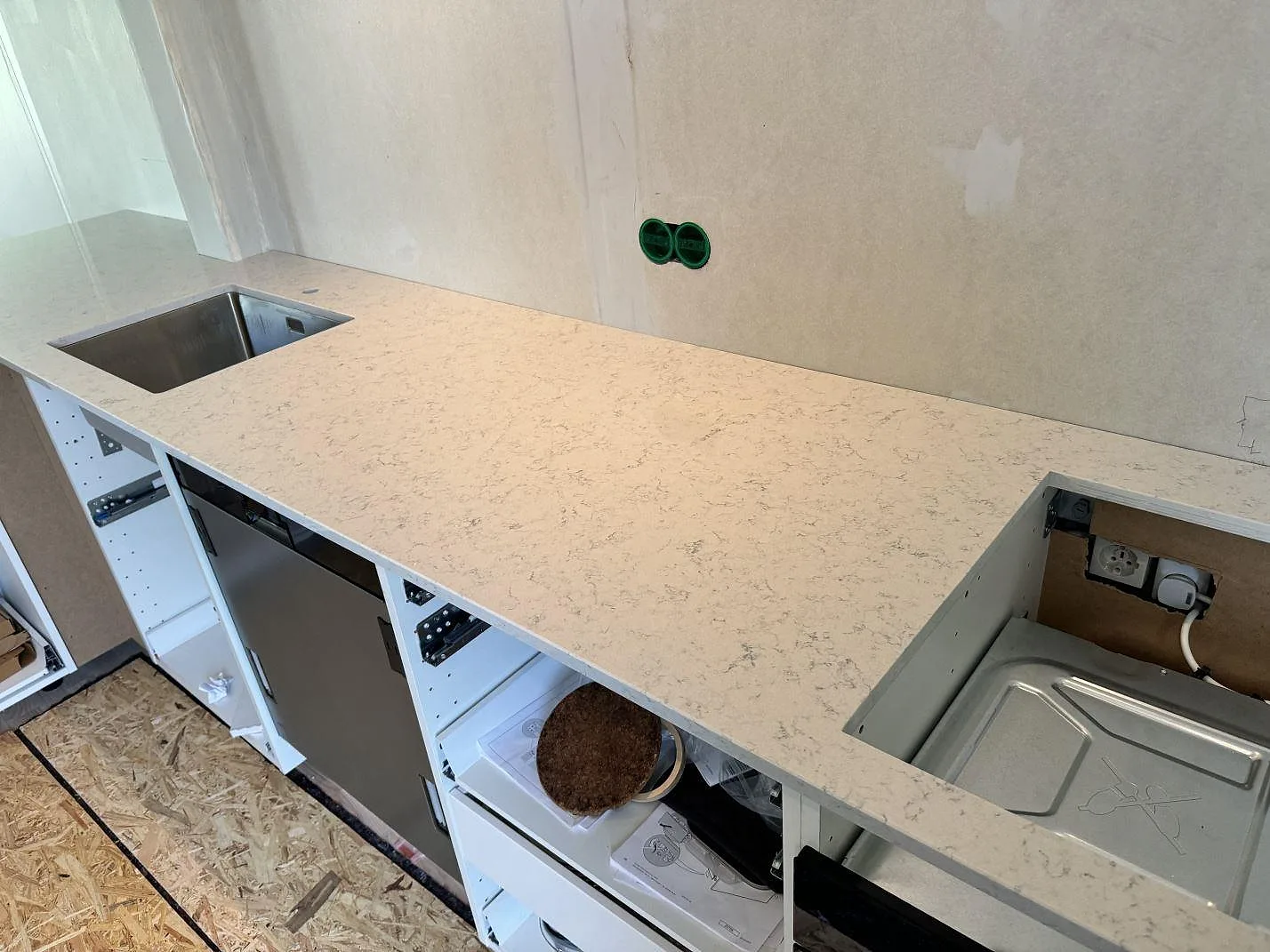 Poleret køkkenbordplade i Technistone Noble Carrara, hvid kvartskomposit, med rostfri vask og större udskæring i ett køkken i Göteborg.