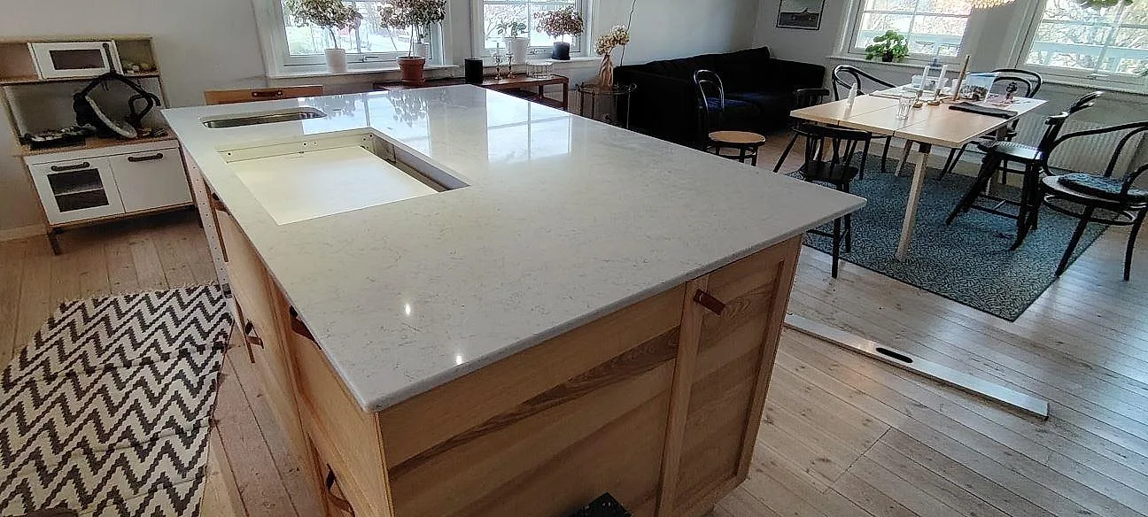 Køkkenø med Bordplade i hvid Technistone Noble Carrara, poleret kvartskomposit, med öppningar i pladen i ett køkken i Nacka.