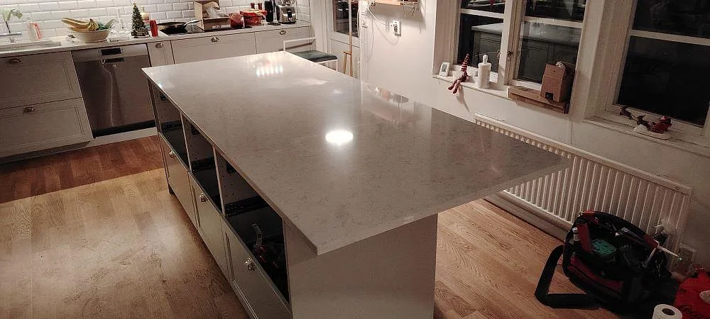 Køkkenø med Bordplade i hvid Technistone Noble Carrara, poleret kvartskomposit, i ett køkken i Täby.