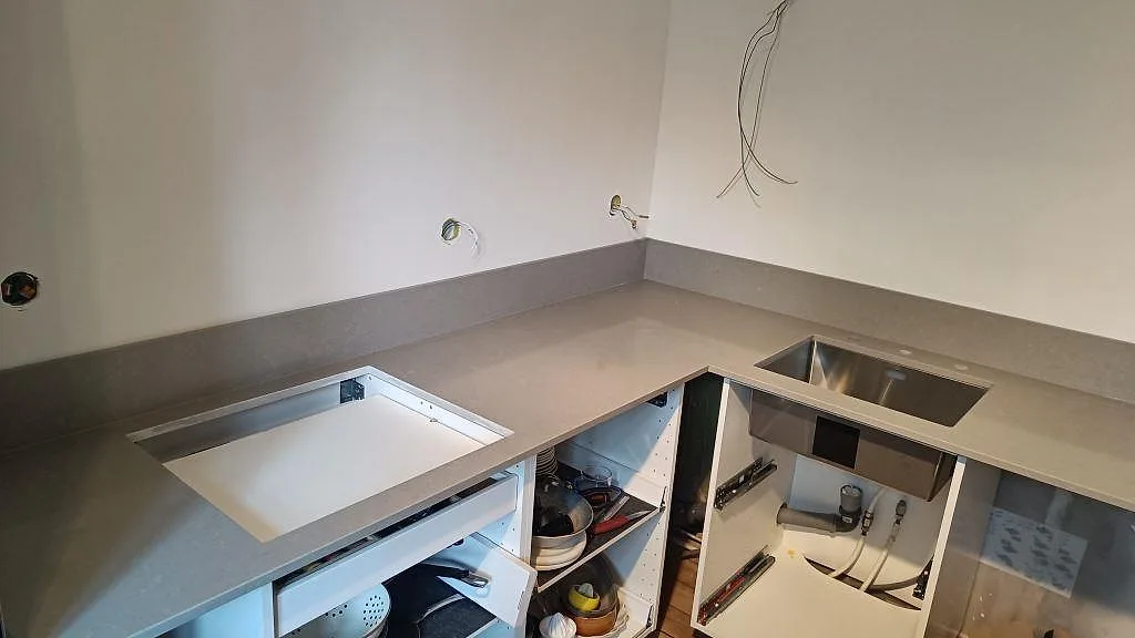 U-formad køkkenbordplade i grå Technistone Noble Concrete Grey, poleret kvartskomposit, med uppvikt stænkplade, hällöppning og rostfri vask i Malmö.