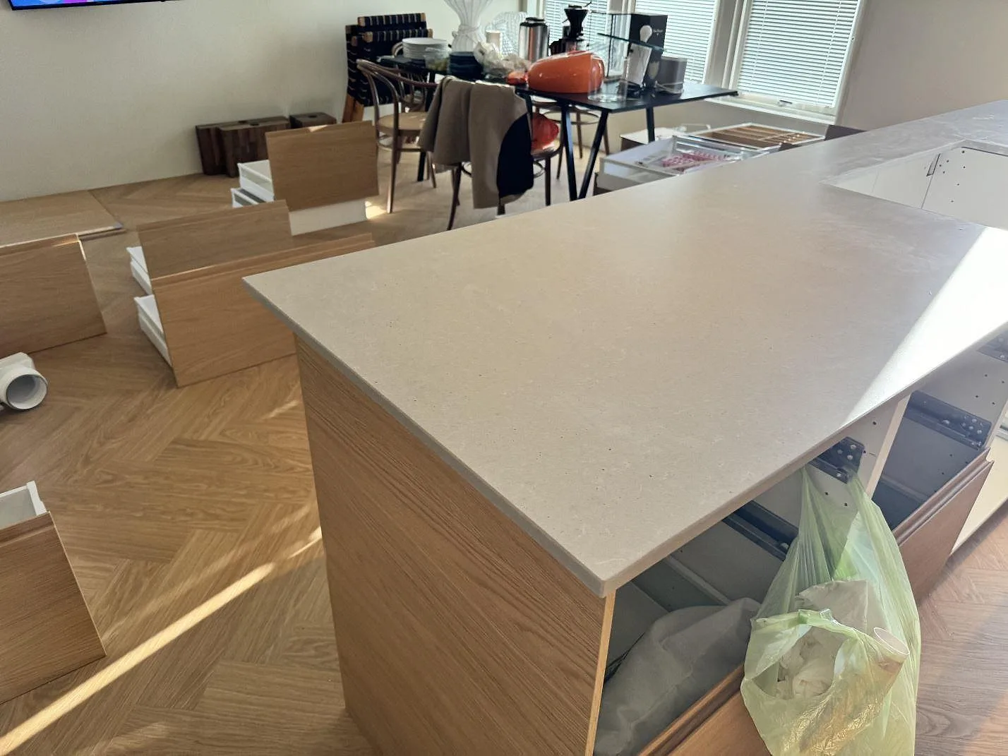 Køkkenbordplade i Technistone Noble Concrete Grey, mat grå komposit, som större arbetsyta på lyse trästommar under montering i Mölndal.