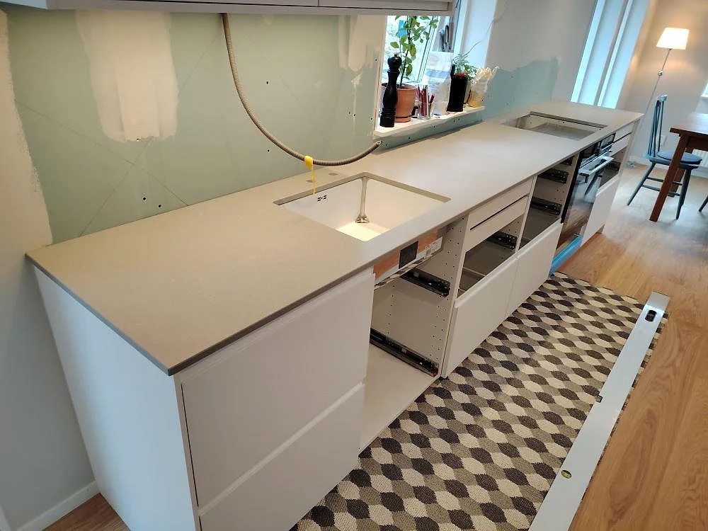 Køkkenbordplade i Technistone Noble Concrete Grey, mat komposit, monteret på öppna vita köksstommar i Sollentuna.