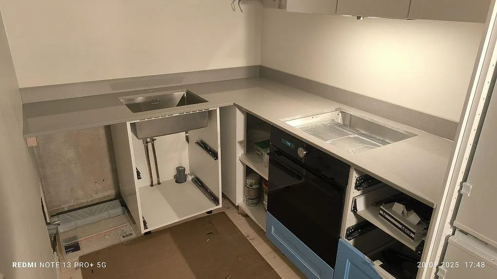 Køkkenbordplade i grå Technistone Noble Concrete Grey, poleret kvartskomposit, med vask, hällöppning og stänkkant i ett køkken i Stockholm.