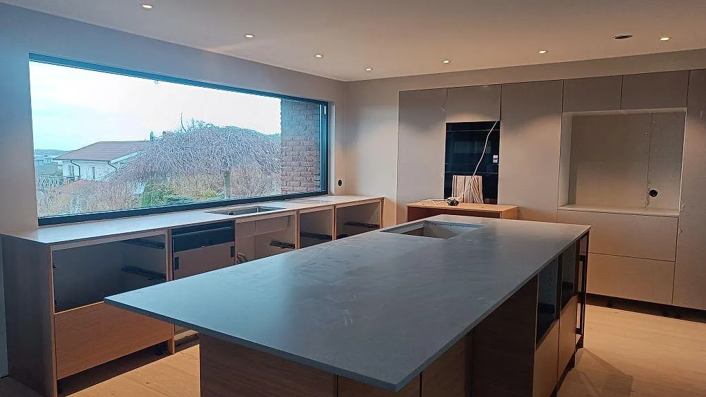 Køkkenbordplade og køkkenø i mat Technistone Noble Concrete Grey, 20 mm kvartskomposit, i ett køkken under montering i Västra Frölunda.