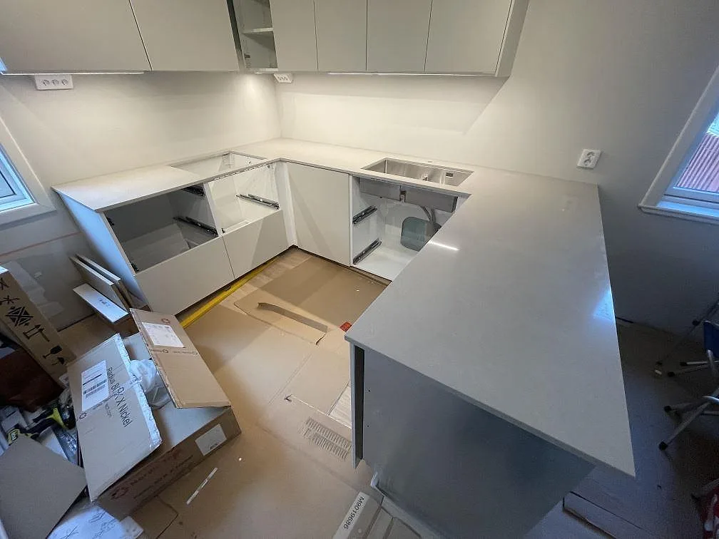 Køkkenbordplade i poleret Technistone Noble Ivory White, 20 mm komposit, i ett U-format køkken med halvö, vask og hällzon i Bromma.