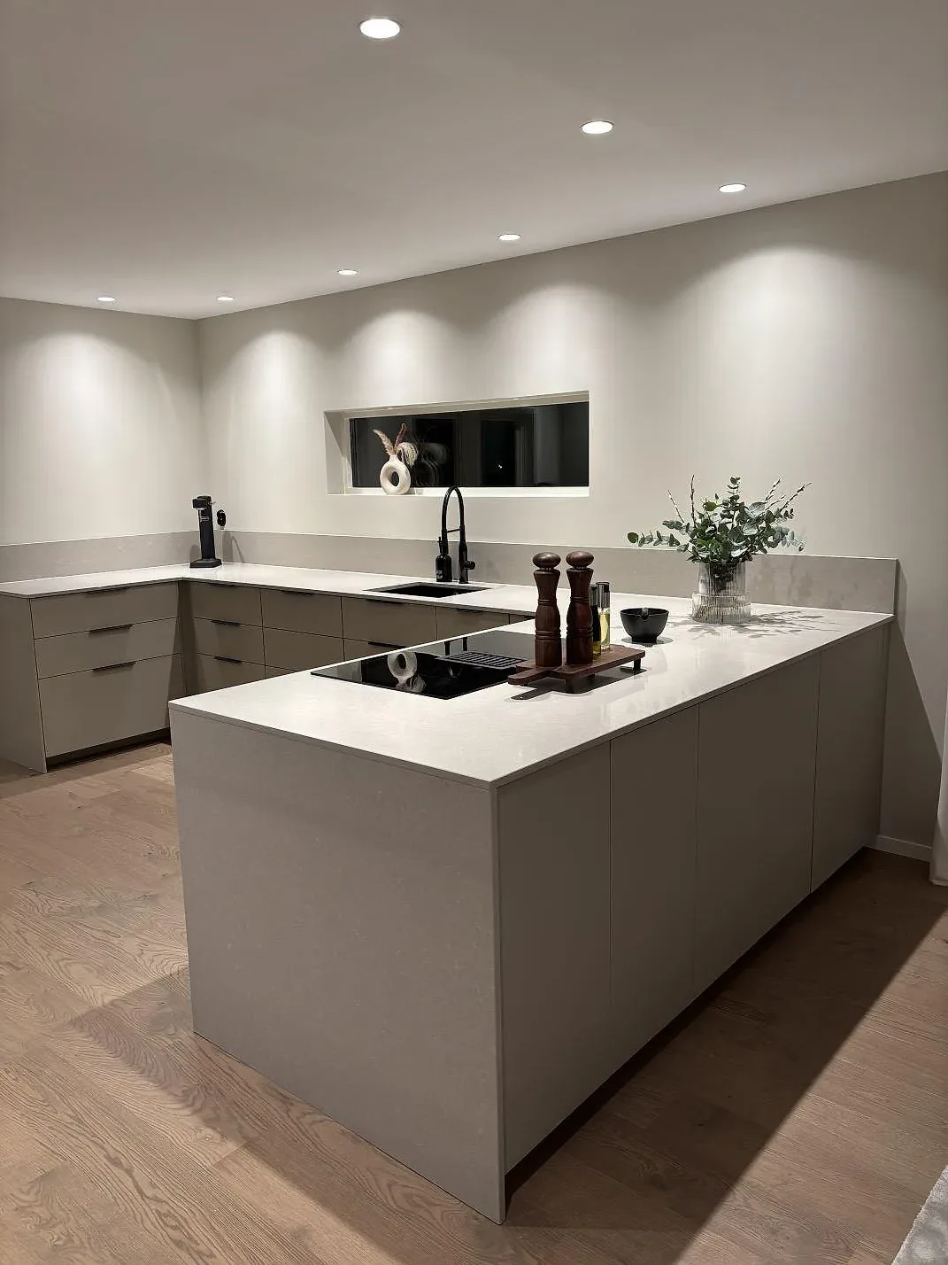 Køkkenbordplade i poleret Technistone Noble Ivory White, 20 mm kvartskomposit, på køkkenø og bakre bordplade i ett køkken i Gnosjö.