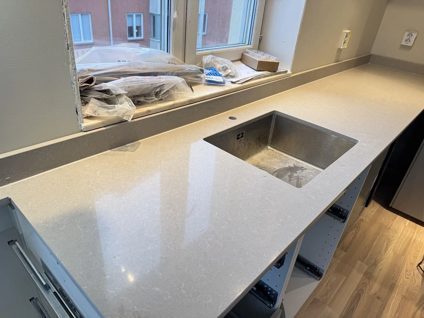 Køkkenbordplade i Technistone Noble Ivory White, poleret kvartskomposit, med rostfri vask og låg stänkkant i ett køkken i Göteborg.